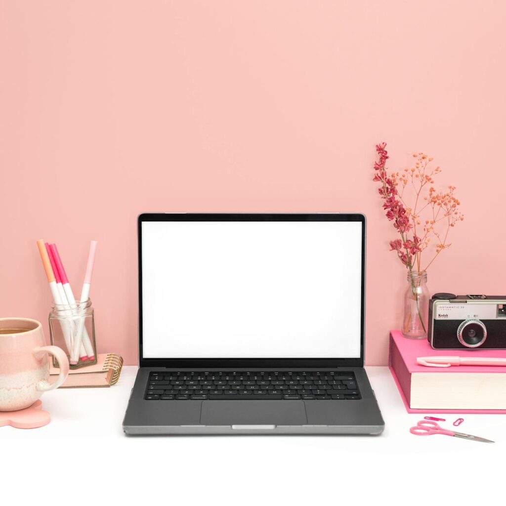 pink aesthetic desk with laptop and vintage camera